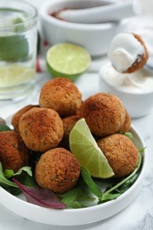 Delicious falafel balls with herbs and lime on white table, closeup