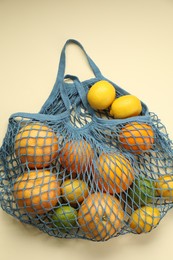 Photo of String bag with different fruits on beige background, top view