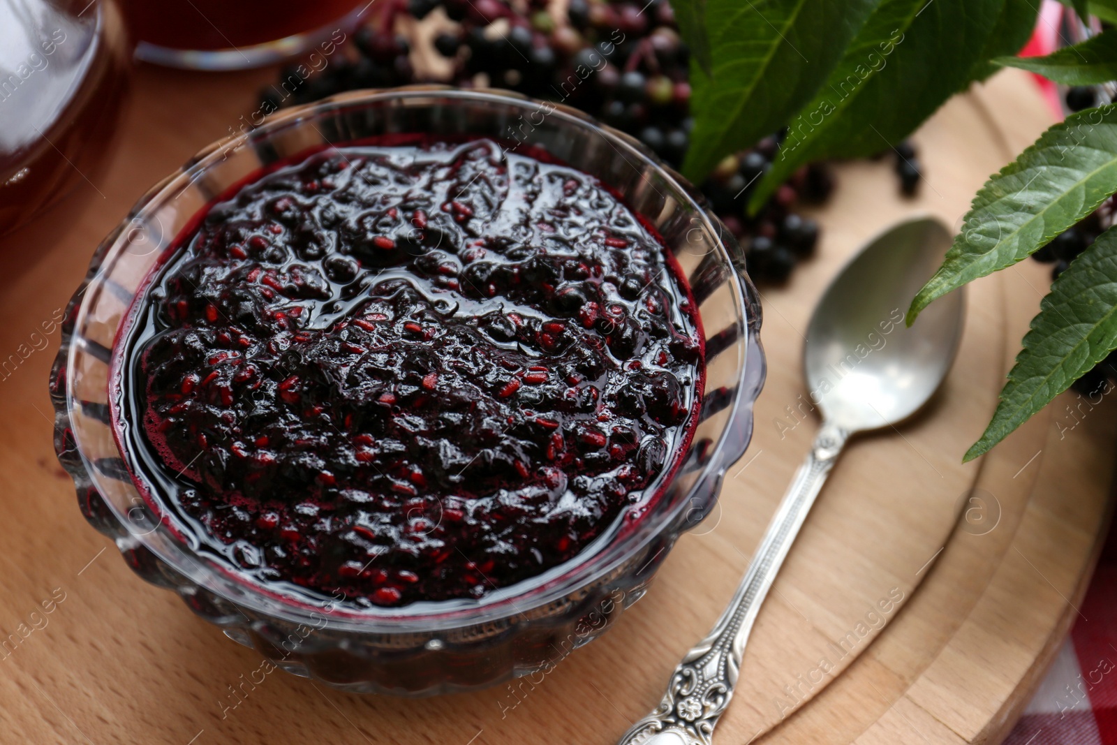 Photo of Elderberry jam with Sambucus berries on table, closeup