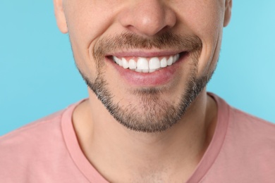 Smiling man with perfect teeth on color background, closeup