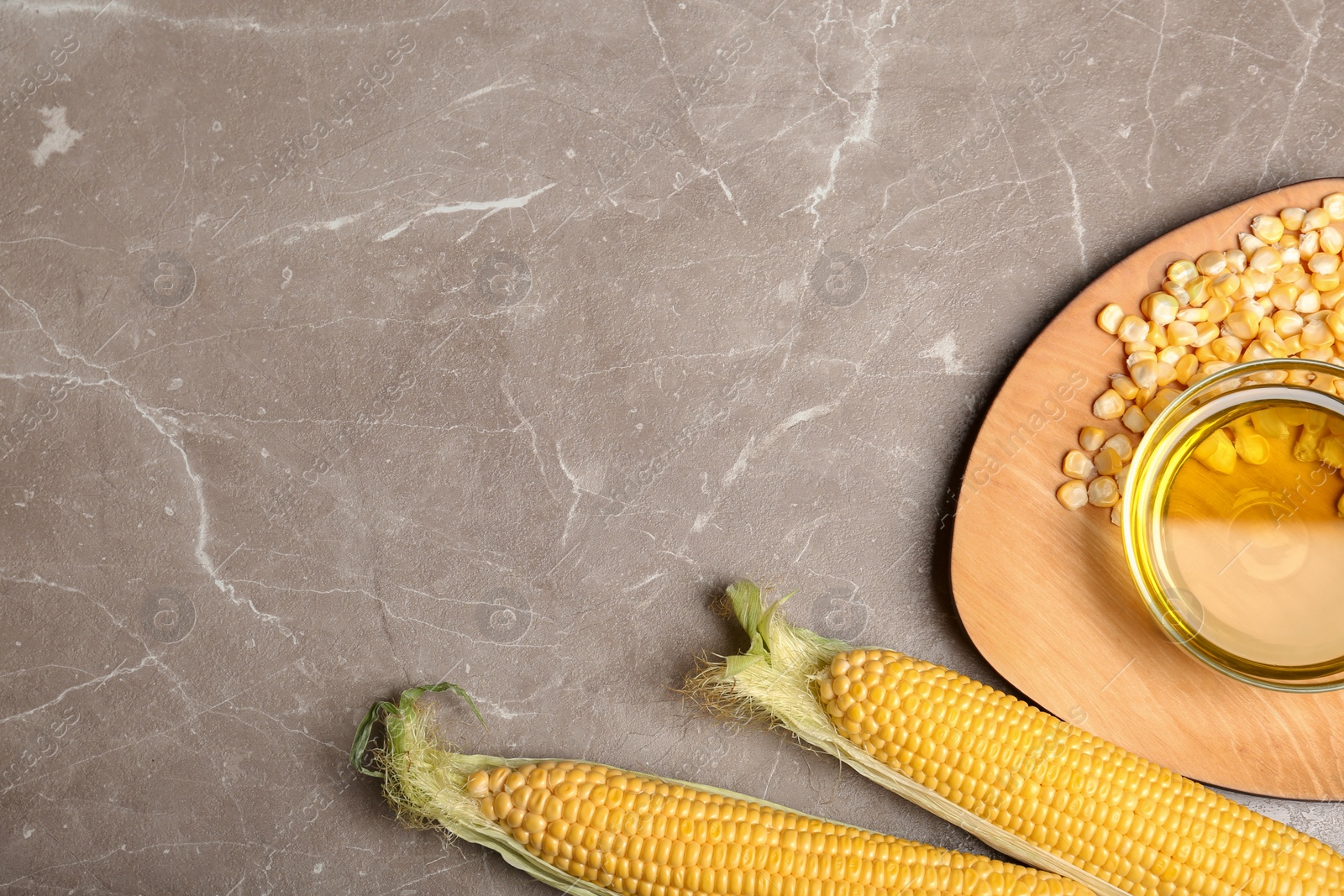 Photo of Flat lay composition with bowl of corn oil, cobs and kernels on gray background