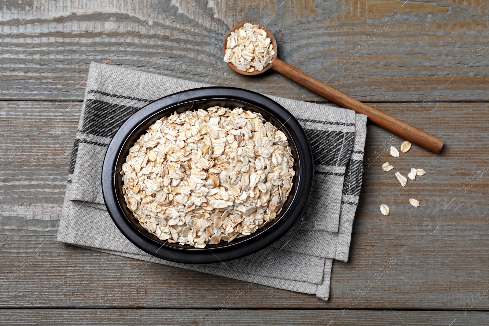 Photo of Bowl and spoon with oatmeal on wooden table, flat lay