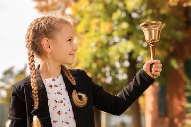 Photo of Pupil with school bell outdoors on sunny day