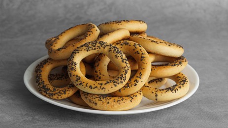 Photo of Plate with delicious ring shaped Sushki (dry bagels) on light grey table, closeup