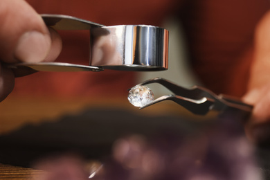 Professional jeweler evaluating beautiful gemstone, closeup view