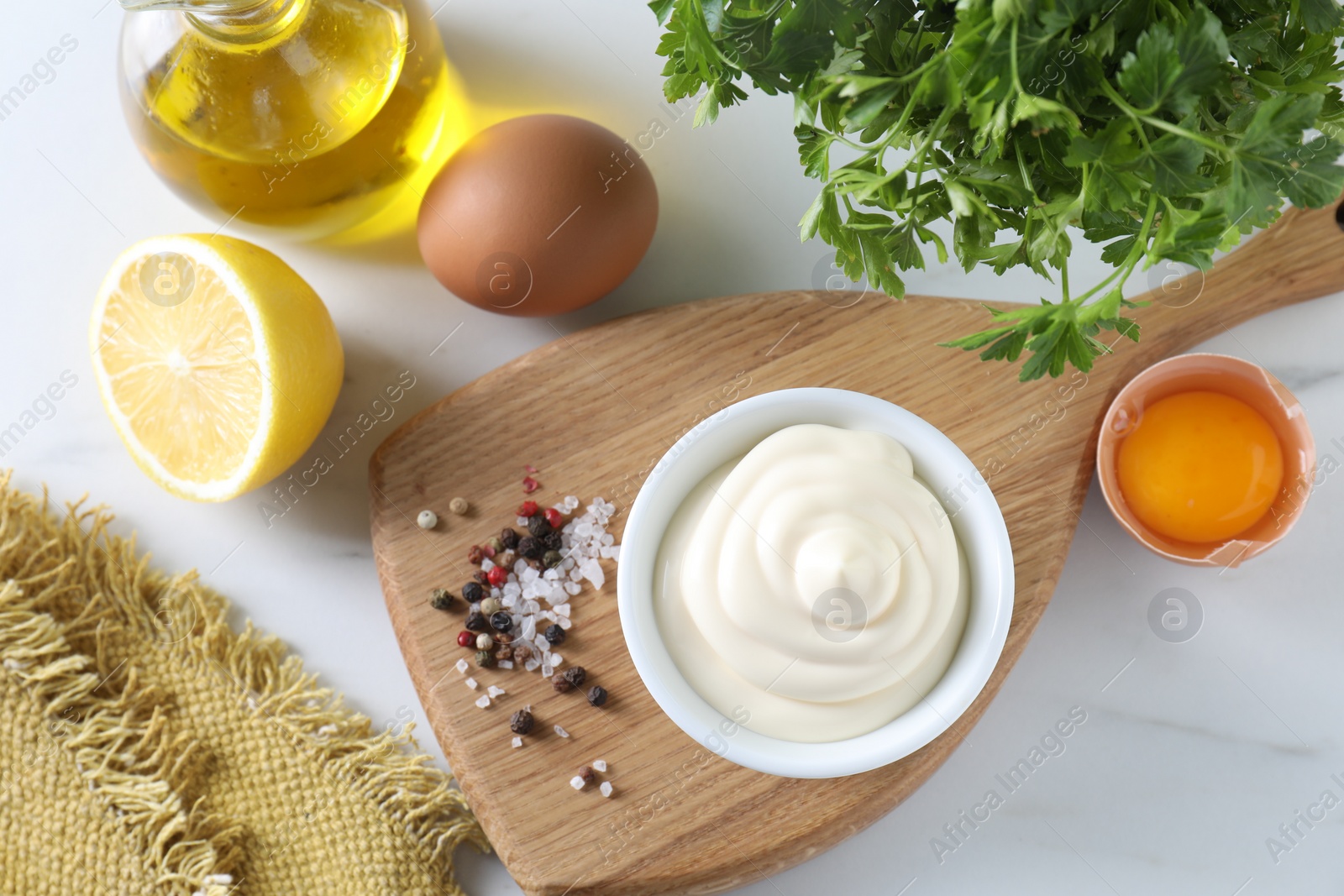 Photo of Tasty mayonnaise sauce in bowl, ingredients and spices on white table, flat lay