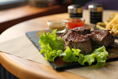 Photo of Tasty pieces of shish kebab served on slate plate in cafe