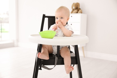 Photo of Cute little baby eating in high chair at home