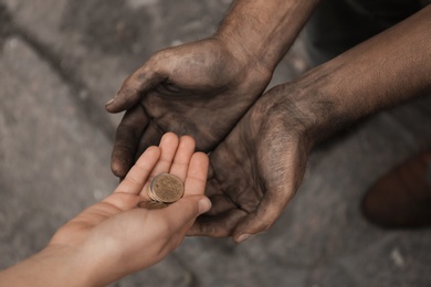 Photo of Woman giving poor homeless person money outdoors, closeup