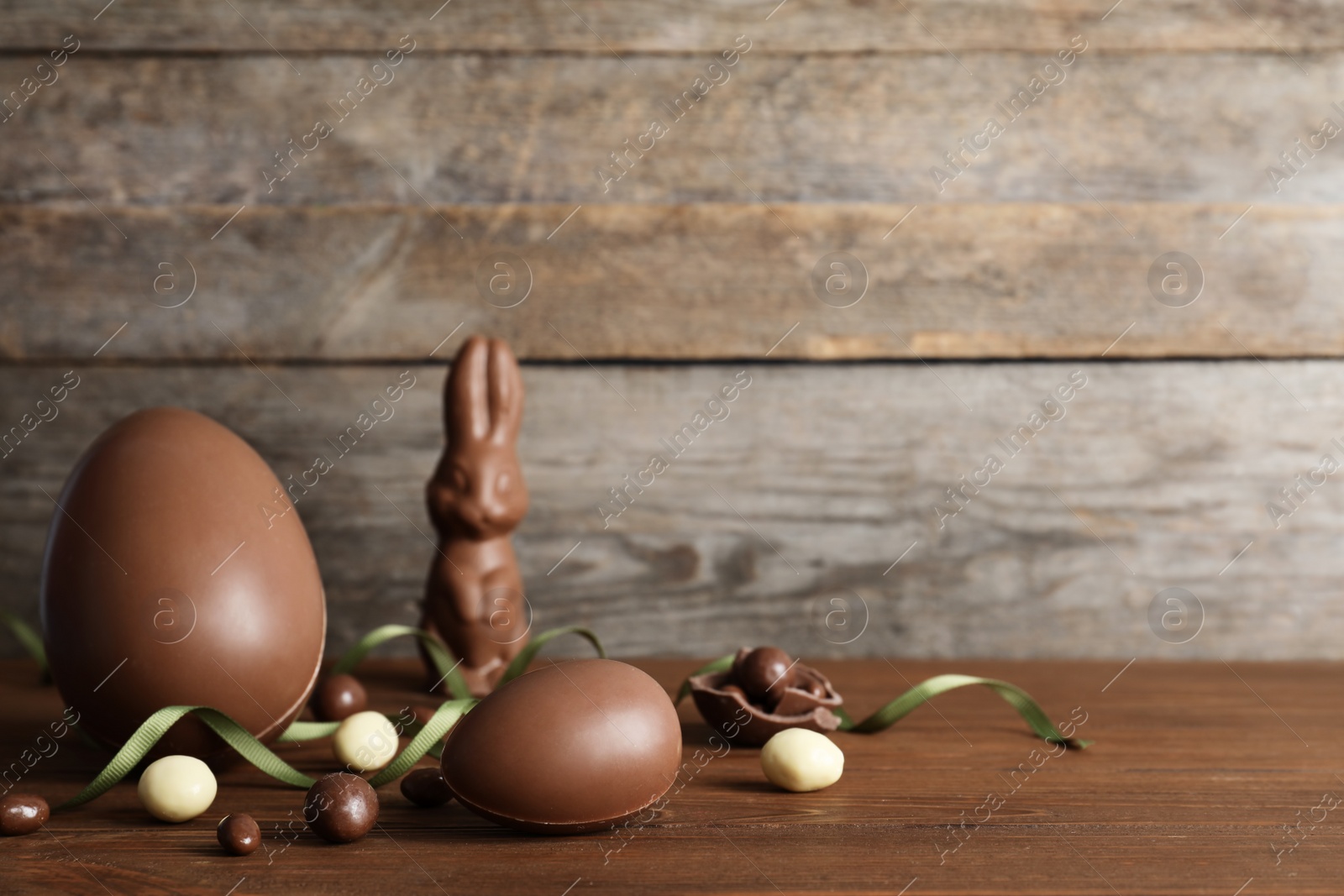 Photo of Beautiful composition with chocolate Easter eggs on wooden table. Space for text