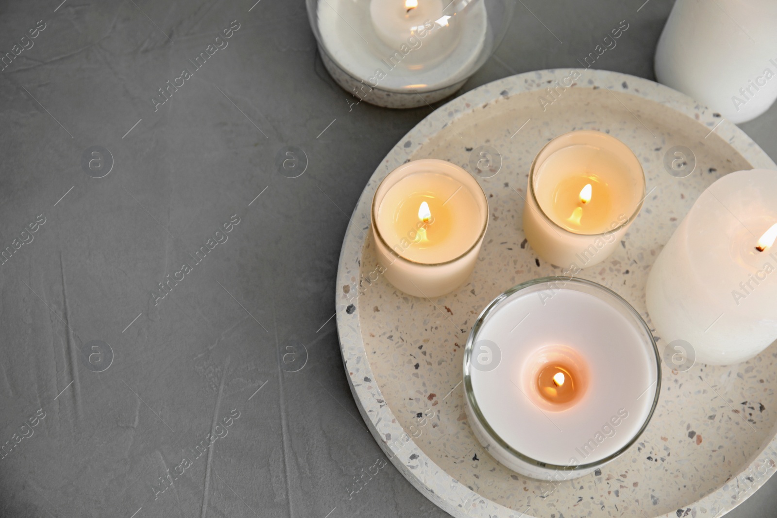 Photo of Flat lay composition with burning aromatic candles on grey table. Space for text