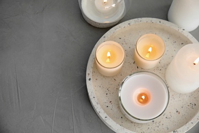 Flat lay composition with burning aromatic candles on grey table. Space for text
