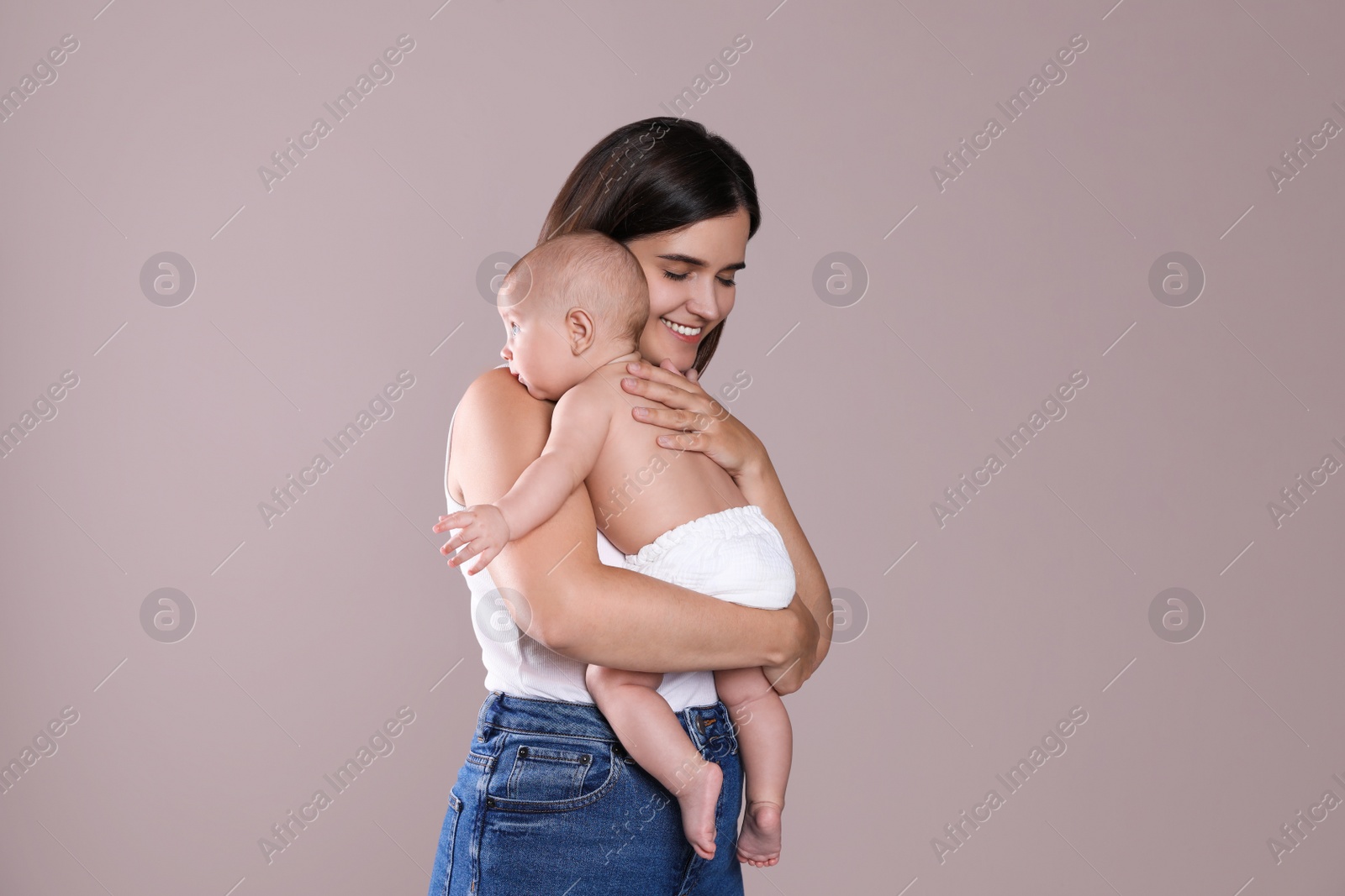 Photo of Beautiful mother with her cute baby on beige background