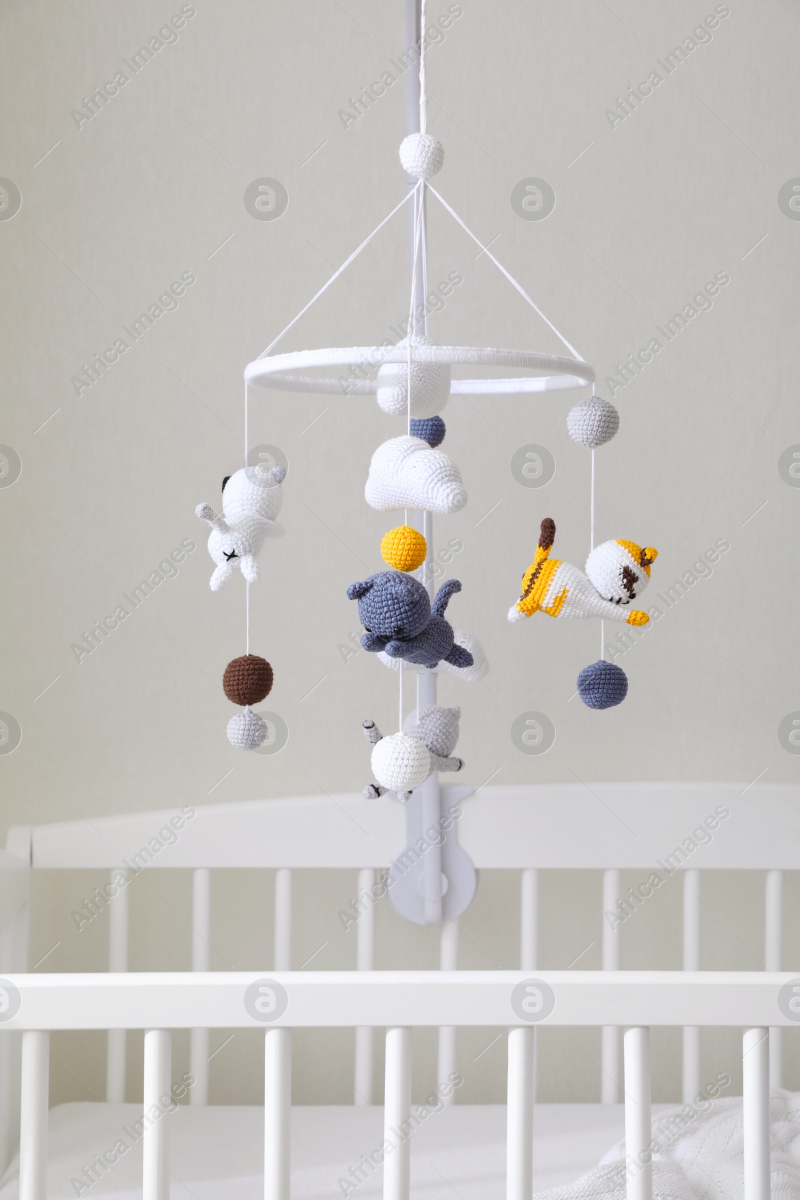 Photo of Modern crib with baby mobile in children's room. Interior design