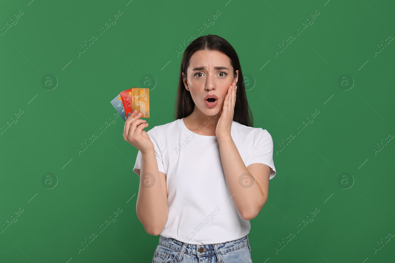 Photo of Shocked woman with credit card on green background. Debt problem