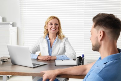 Photo of Doctor consulting patient at table in clinic