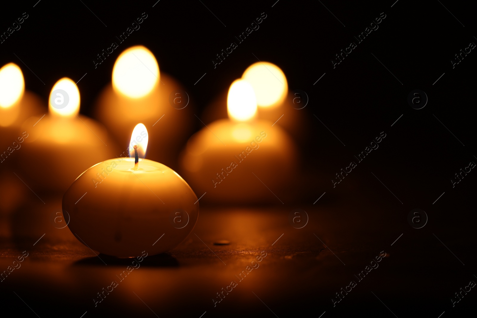 Photo of Many burning wax candles on black background, closeup. Space for text