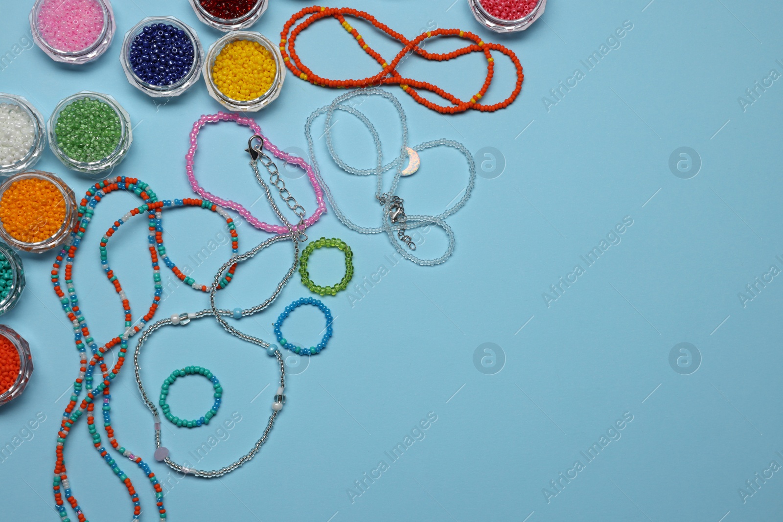 Photo of Flat lay composition with different colorful beads on light blue background, space for text