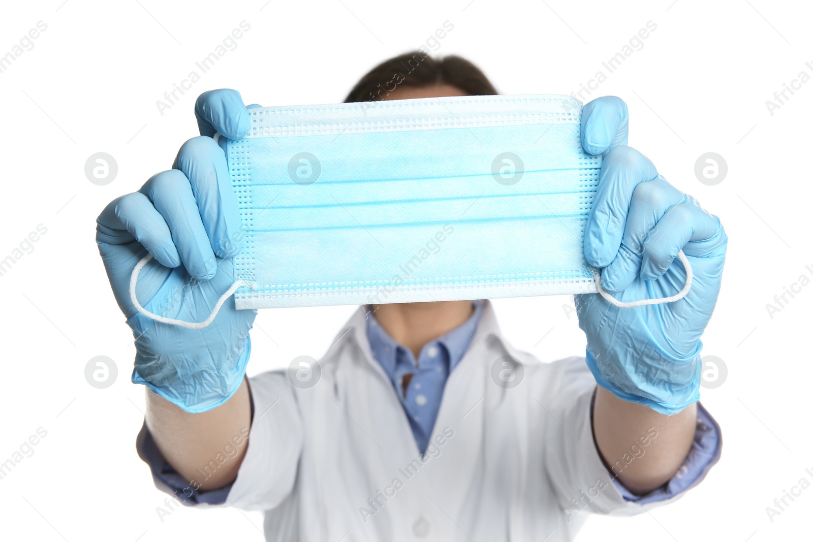 Photo of Doctor in latex gloves holding disposable face mask on white background, closeup. Protective measures during coronavirus quarantine