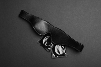 Photo of Leather mask and condoms on black background, top view. Sex game