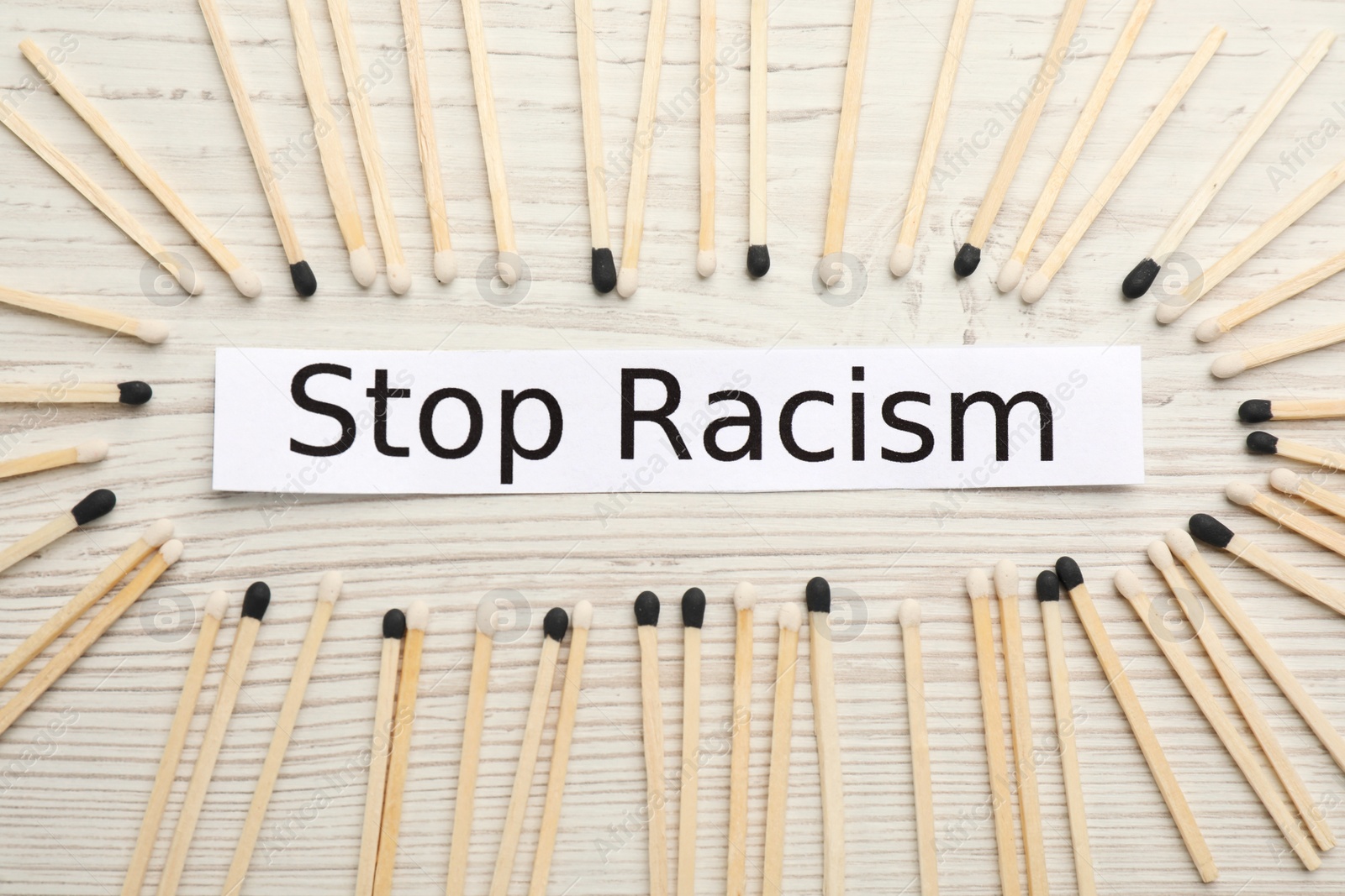 Photo of Phrase Stop Racism and different matches on white wooden table, flat lay