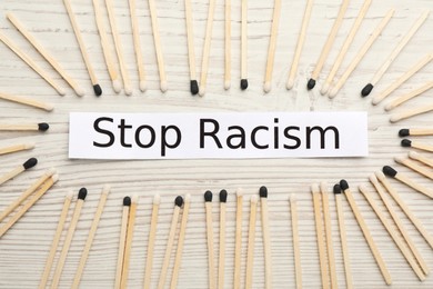 Photo of Phrase Stop Racism and different matches on white wooden table, flat lay