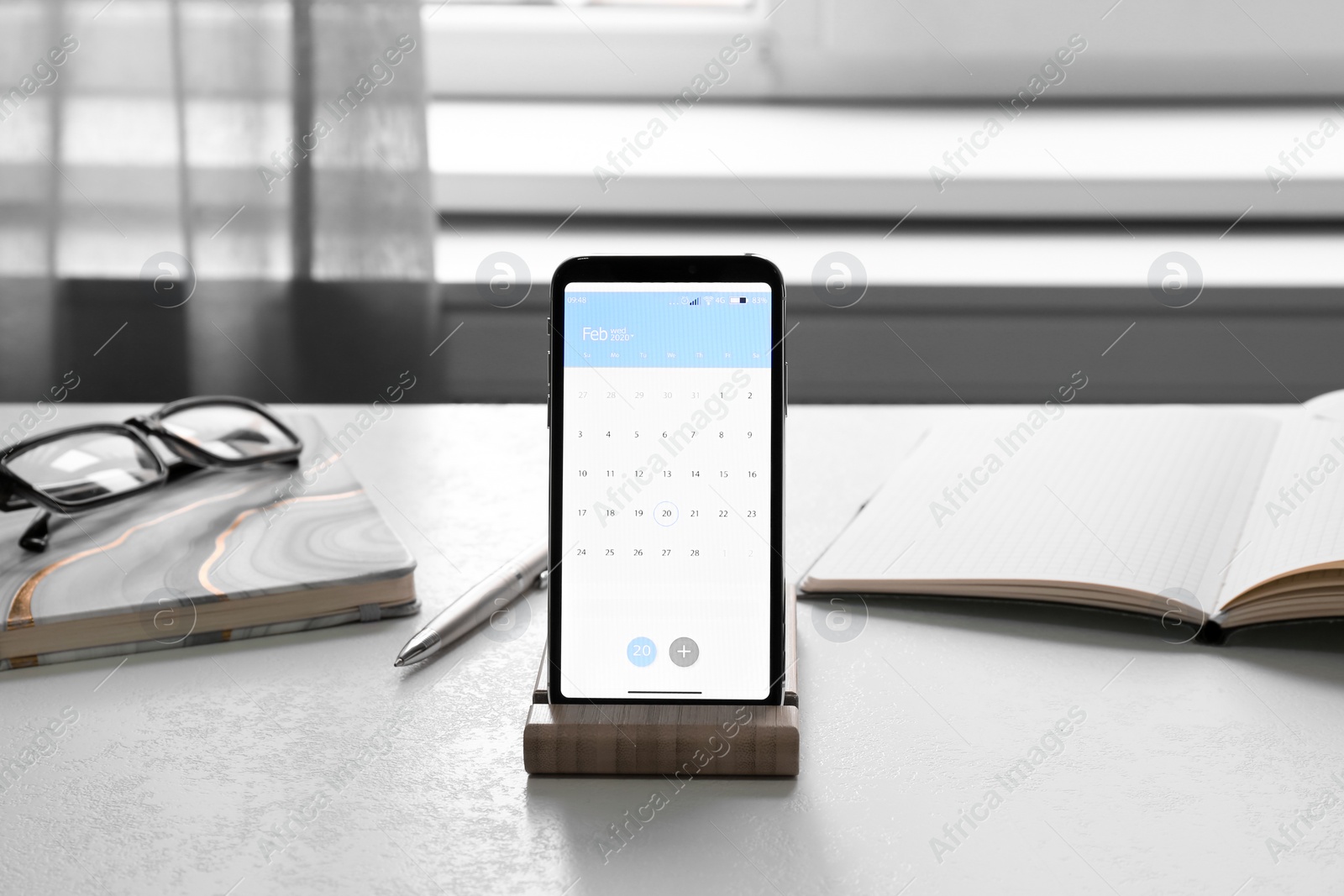 Photo of Modern smartphone with calendar on screen in office