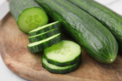 Photo of Fresh whole and cut cucumbers on table, closeup