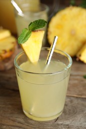 Photo of Delicious pineapple juice and fresh fruit on wooden table