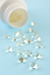 Bottle and vitamin capsules on light blue background, closeup