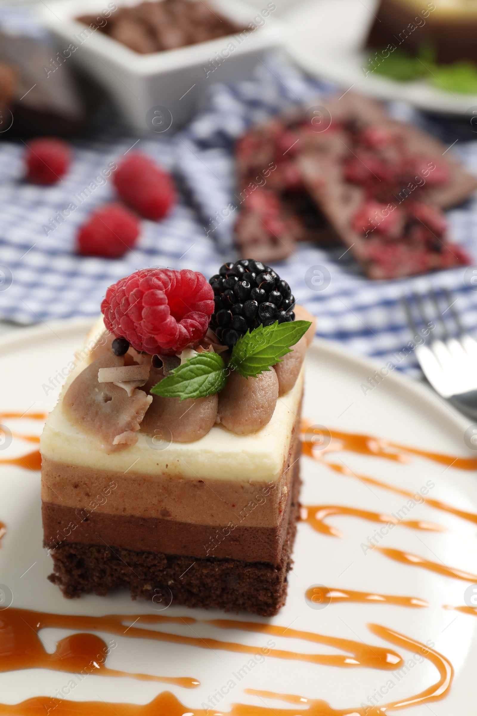 Photo of Piece of triple chocolate mousse cake with fresh berries on table, closeup