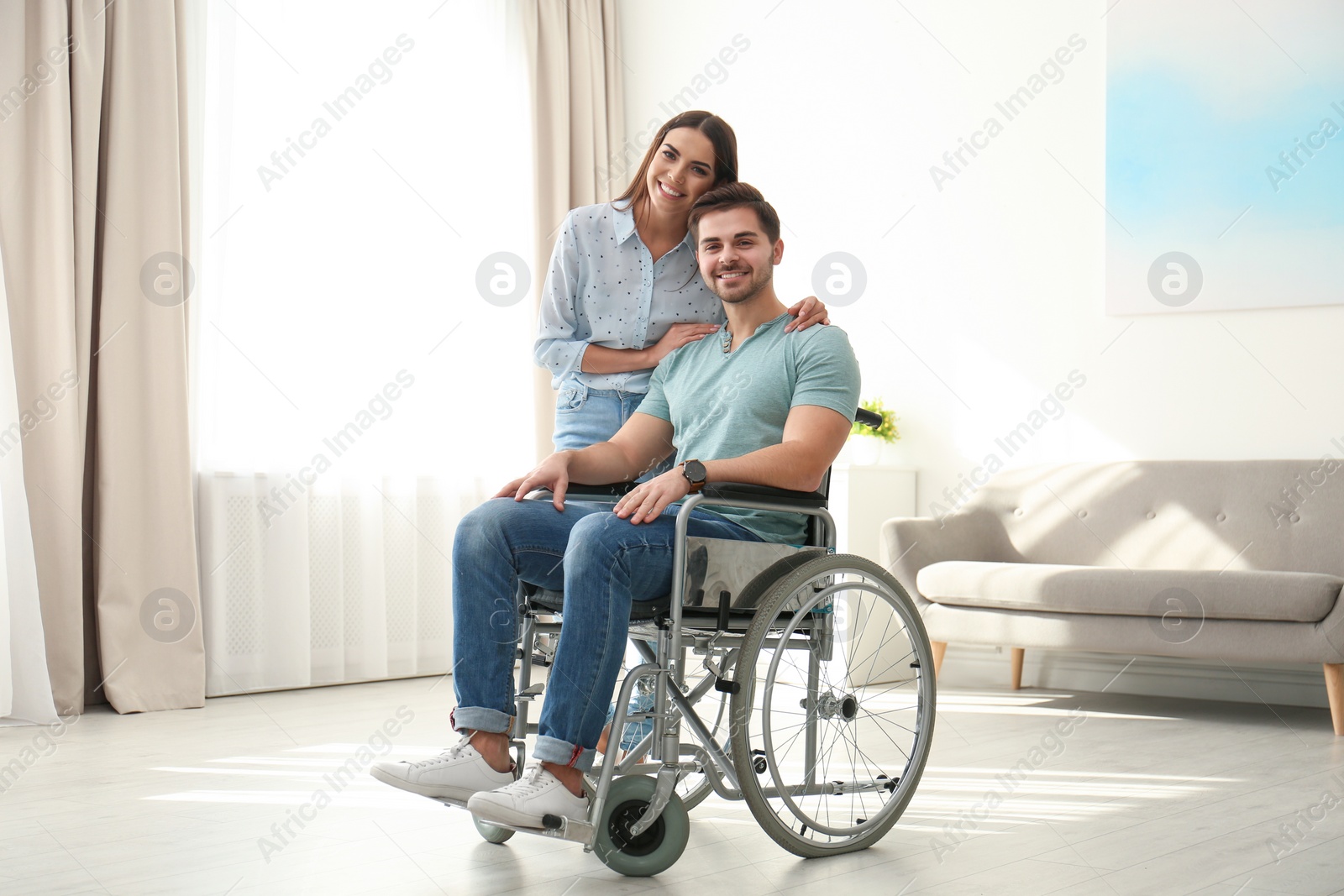 Photo of Young woman with man in wheelchair indoors