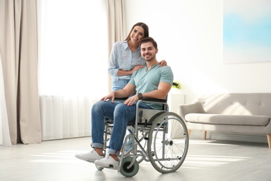Photo of Young woman with man in wheelchair indoors