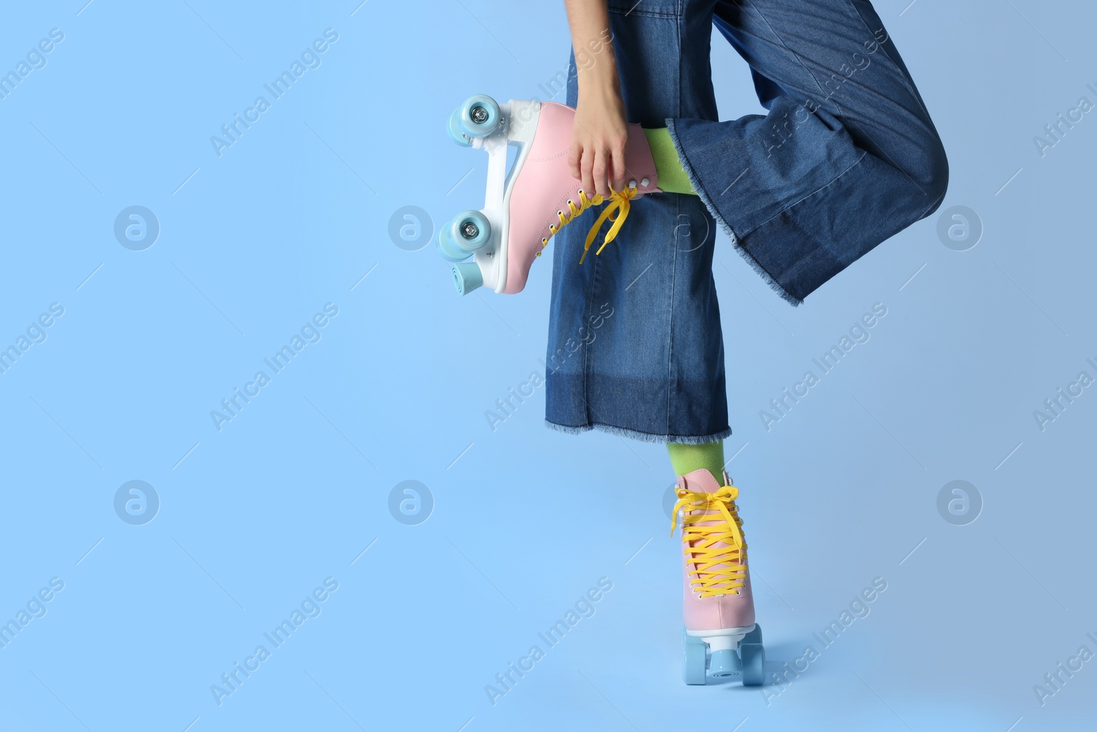 Photo of Woman with vintage roller skates on color background, closeup. Space for text