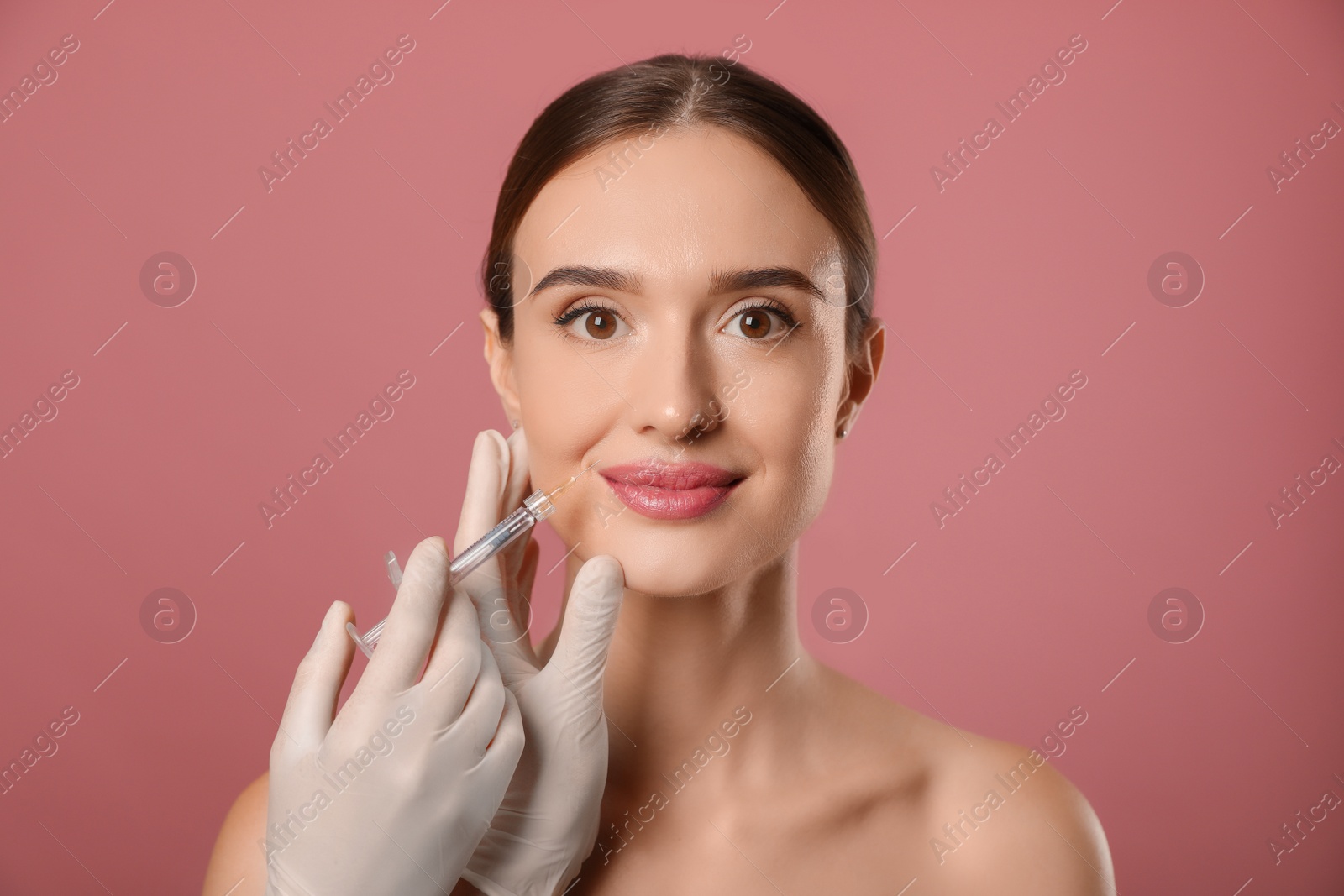 Photo of Beautiful woman getting facial injection on pink background. Cosmetic surgery