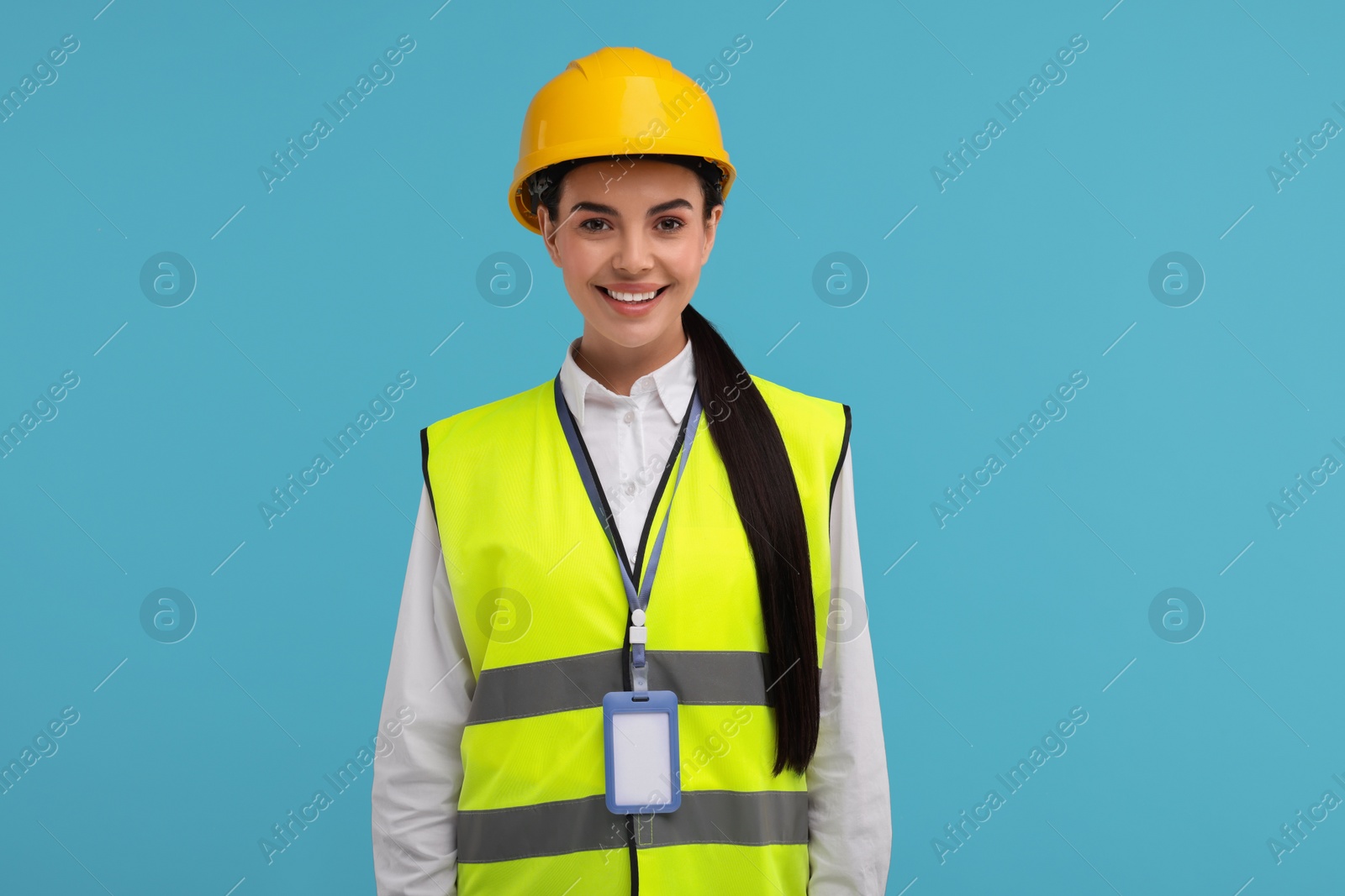 Photo of Engineer with hard hat and badge on light blue background