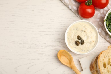 Photo of Creamy caper sauce in bowl on white wooden table, flat lay. Space for text