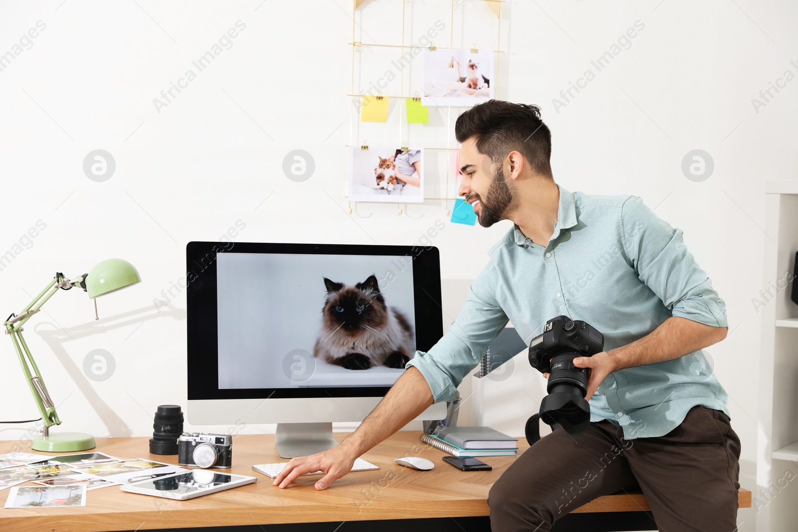 Photo of Professional photographer with camera working in light modern office