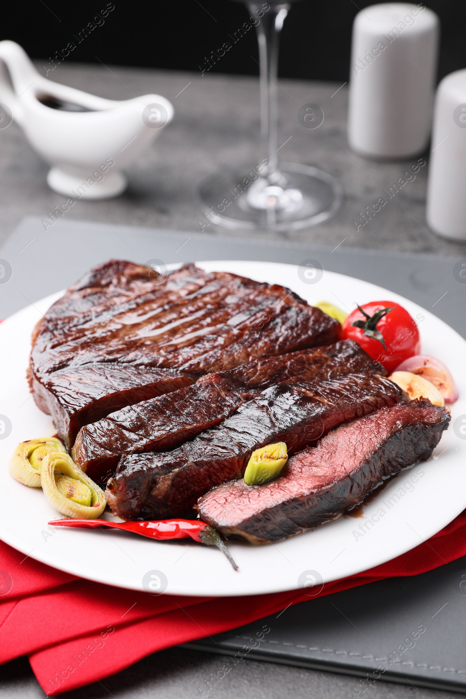 Photo of Delicious grilled beef meat served on grey table, closeup