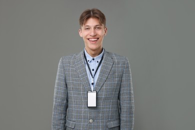 Happy man with blank badge on grey background