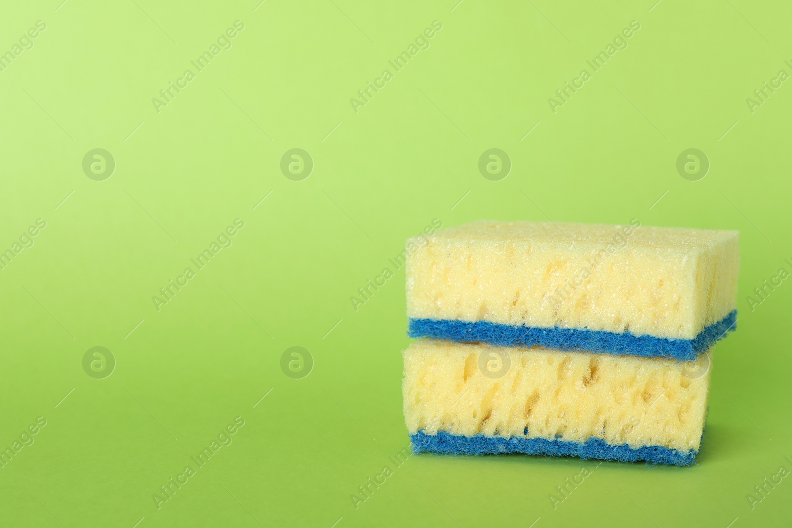 Photo of Sponges on green background. Space for text