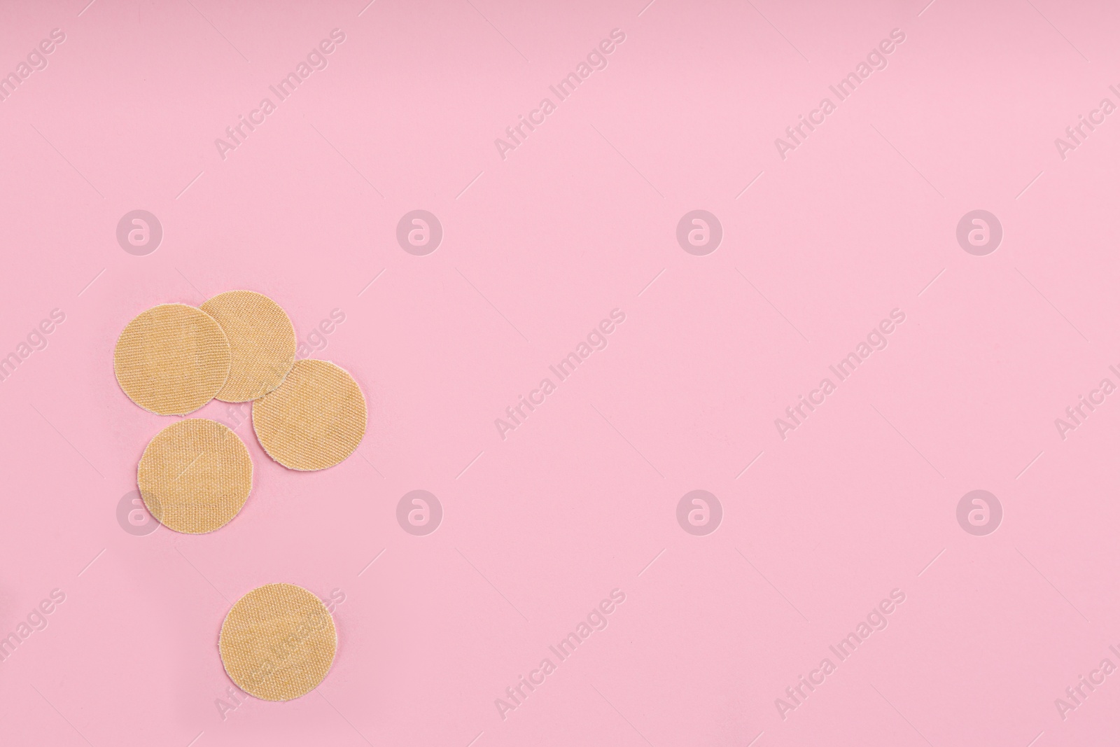 Photo of Sticking plasters on pink background, flat lay. Space for text
