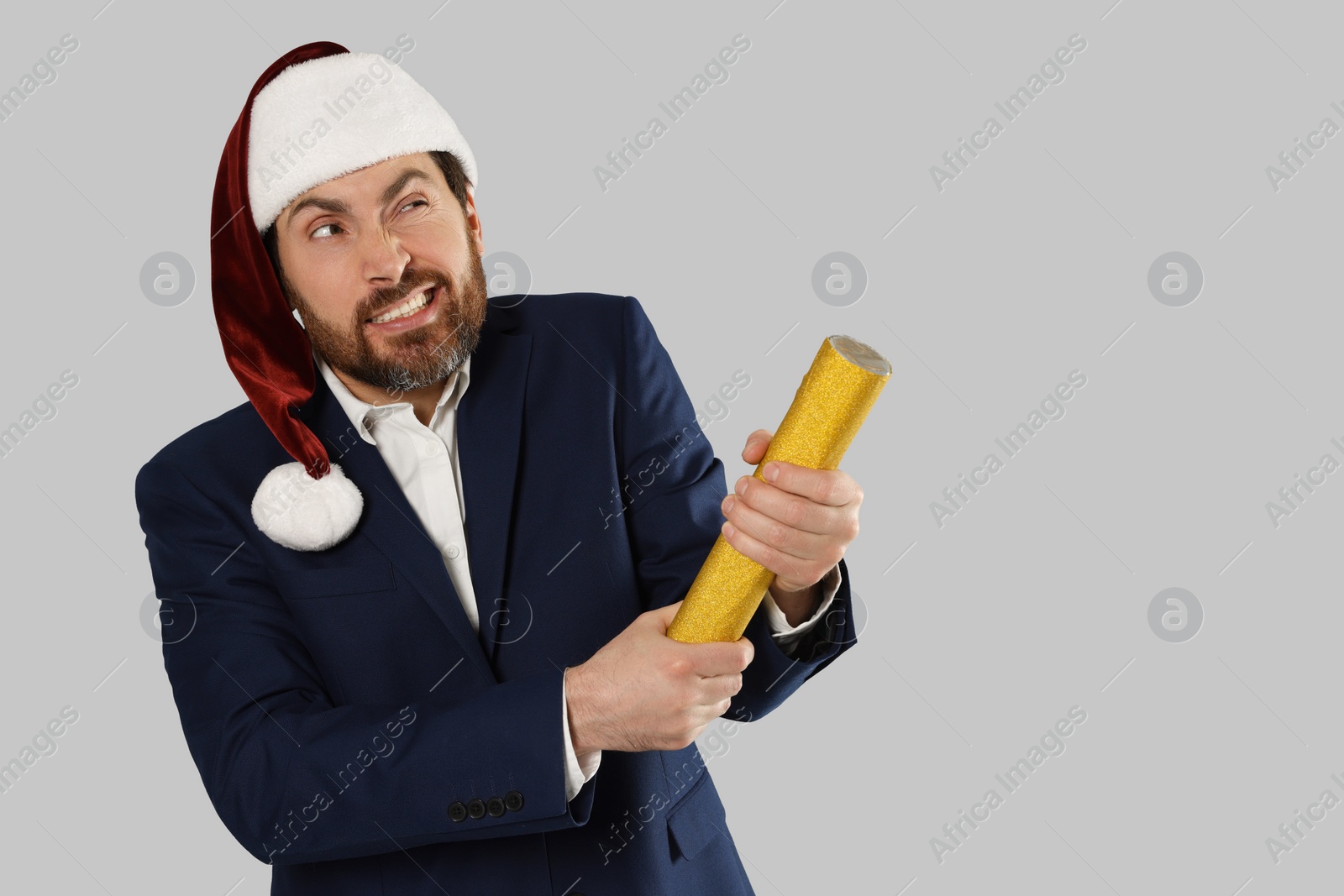 Photo of Emotional man with party popper on light grey background. Space for text