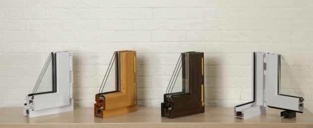 Samples of modern window profiles on table against brick wall. Installation service