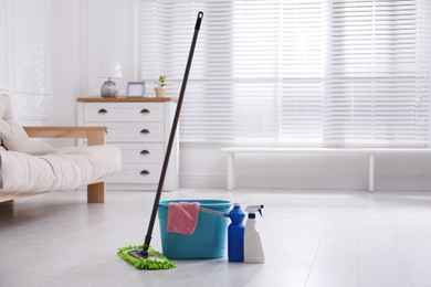 Photo of Mop and cleaning supplies on floor in room