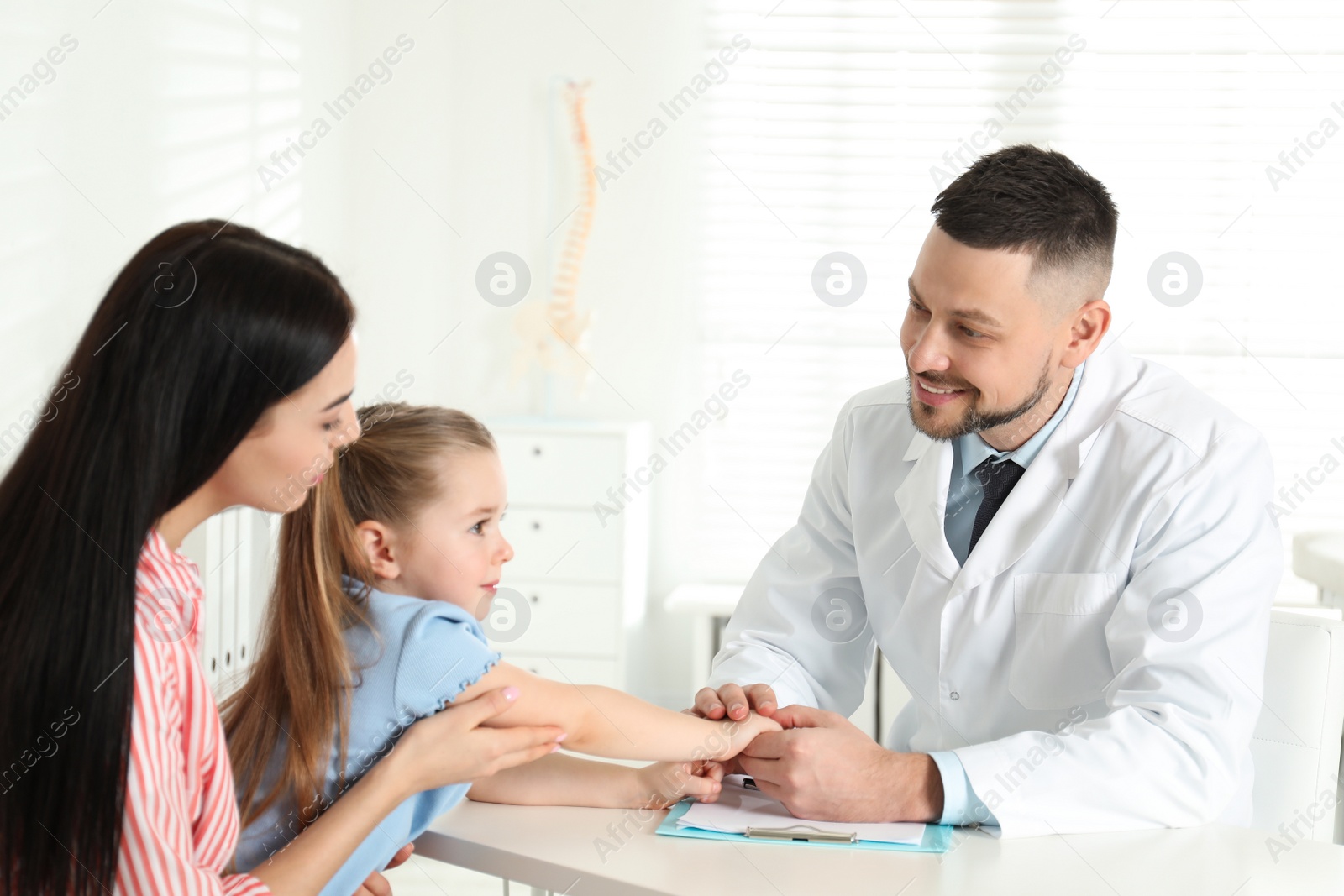 Photo of Little girl with mother visiting orthopedist at clinic