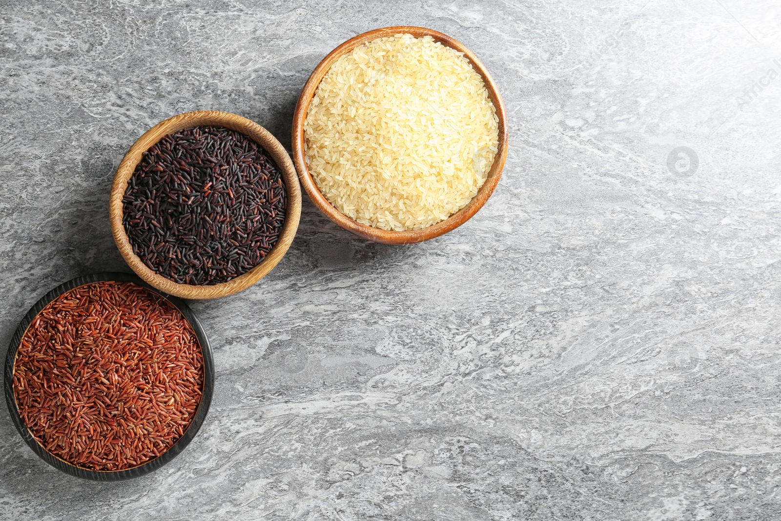 Photo of Flat lay composition with brown and other types of rice in bowls on grunge background. Space for text