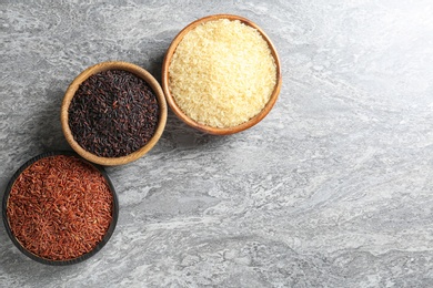 Flat lay composition with brown and other types of rice in bowls on grunge background. Space for text