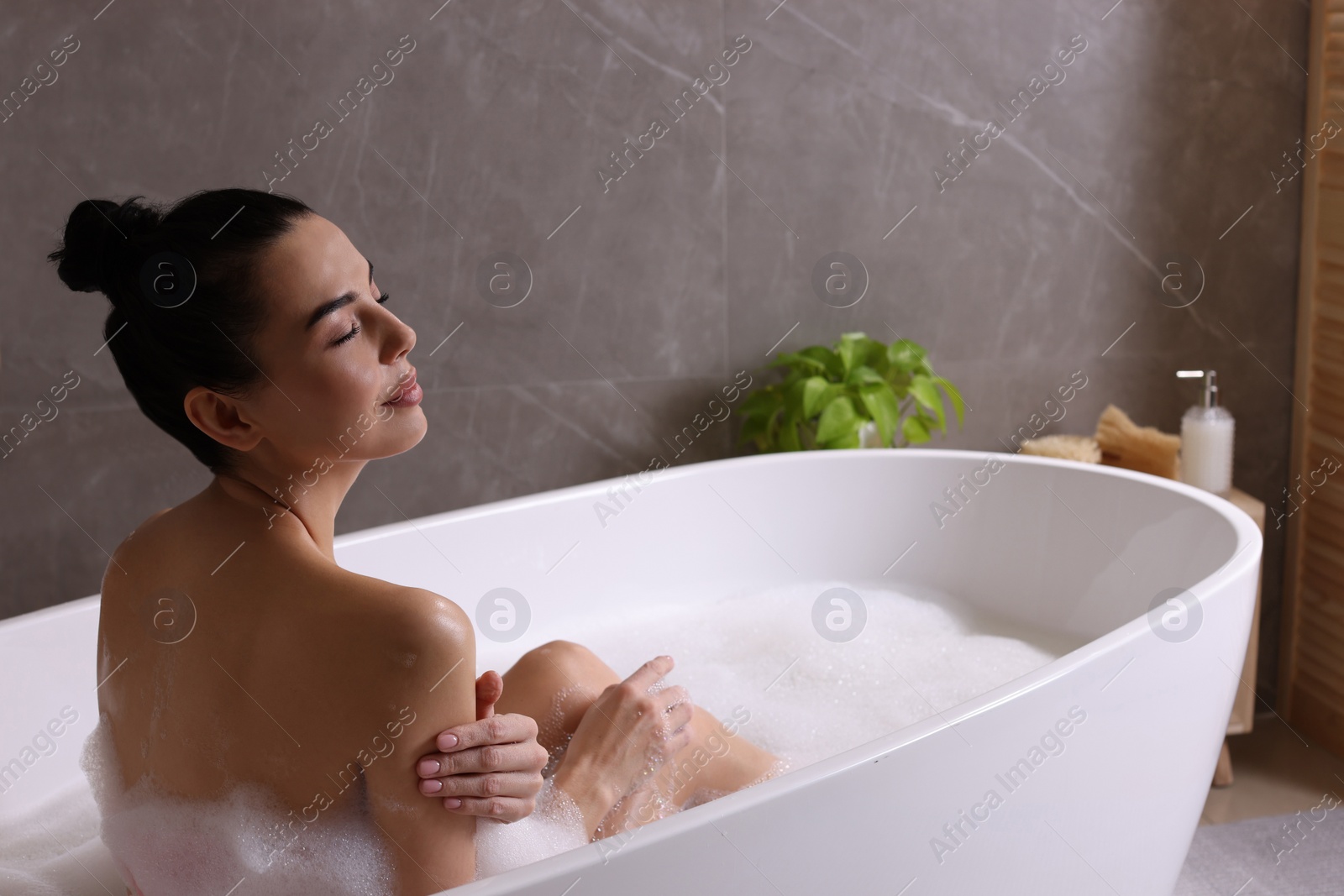 Photo of Woman taking bath with shower gel indoors