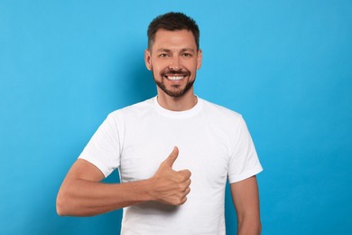 Photo of Man showing thumb up on light blue background